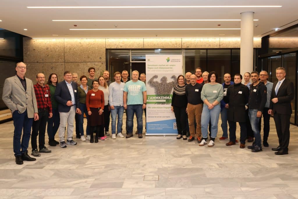 Gruppenbild im Foyer des Landratsamts. In der Bitte steht ein Rollup mit einer starken Person und dem Wort "Zammkemma"