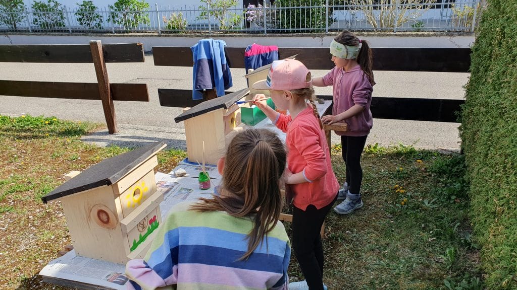 Kinder bemalen im Freien Vogelhäuschen.