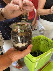 Eine Person befüllt ein Glas mit Erde.